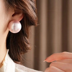 Close-up of a model wearing a large pink round pearl stud earring with elegant luster