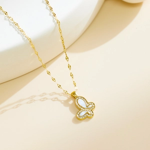 Detail of golden butterfly pendant with white shell inlay and sparkling cubic zirconia