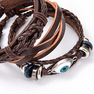 Detail of multilayer leather bracelet with brown braided ropes and blue evil eye charm