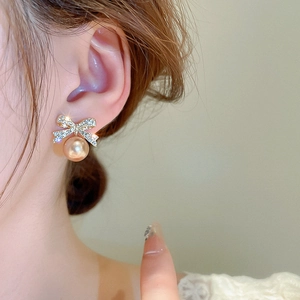 Gros plan de boucles d'oreilles nœud scintillant avec diamants et perles dorées