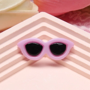 Mini pink resin cat-eye sunglasses charm on a tiered display stand for DIY crafts