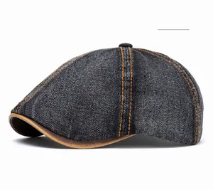 Detail of dark denim flat cap with orange contrast stitching and brown leather brim