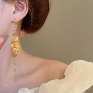 Close-up of long yellow floral tassel earrings with metal chains worn by a model