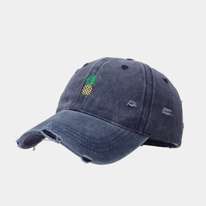 Détail d'une casquette bleue marine délavée avec broderie d'ananas et bords effilochés