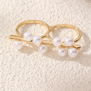 Detailed close-up of a double-band gold ring with eight elegant white pearls on stone