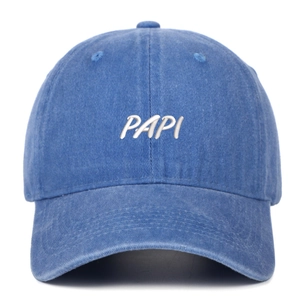 Close-up of embroidered PAPI letters on a washed denim baseball cap in vintage blue