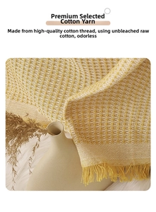 Detail of yellow waffle weave cotton throw blanket featuring natural fringe edges