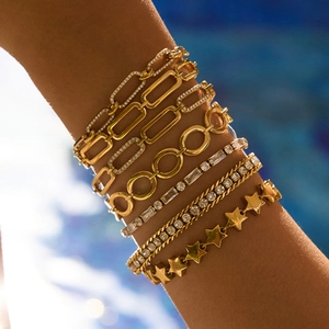 Gros plan de 7 bracelets dorés empilés avec breloques étoiles et pierres de zircon