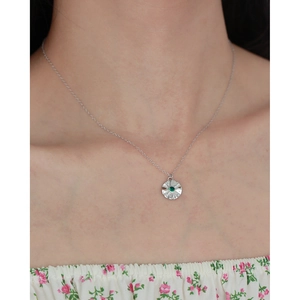 Detailed view of silver necklace with starburst emerald pendant on model neckline