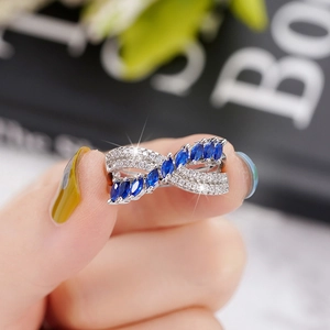 Detailed close-up of a silver crossover ring featuring a blue marquise-cut gemstone