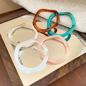 Set of five wavy irregular acrylic resin bangles in amber, cream, and green shades