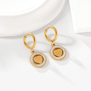 Détail de boucles d'oreilles cœur dorées avec zircons blancs sur un fond blanc