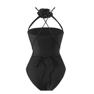Detail of black halter swimsuit featuring a large floral applique and crisscross back straps