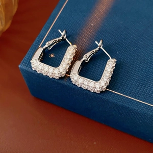 Vue macro de boucles d'oreilles créoles carrées en argent avec zircons sur un écrin