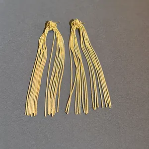 Elegant gold metal tassel earrings with flowing snake chain design on dark background