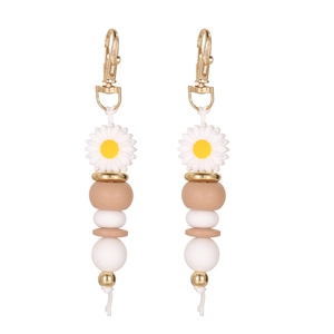 Close-up of silicone daisy bead keychain with golden clasp and tassels in white and yellow