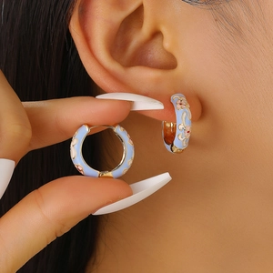 Vintage light blue enamel hoop earrings with pink flower patterns on female model ear