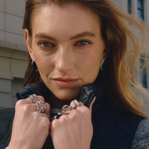 Close-up of mixed metal rings and black stud earrings with cubic zirconia on a model