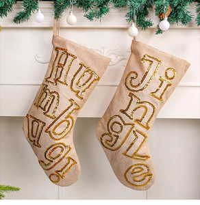Detail of linen Christmas stockings with gold sequins and embroidery hung on fireplace