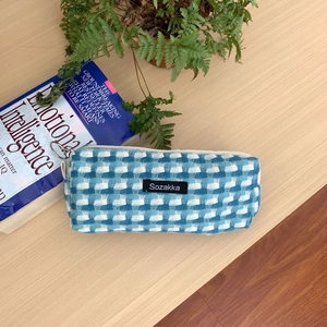 Gros plan d'une trousse à carreaux bleus et blancs avec logo sur bureau en bois