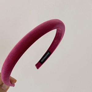 Detail shot of a thick rose red velvet padded headband featuring a handmade inner label
