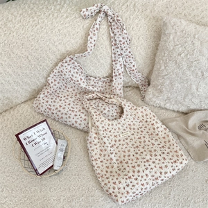 Close-up detail of floral canvas tote bag featuring delicate pink flower print and brand tag