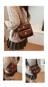 Detail view of brown vintage messenger bag with dual gold twist locks and woven charm