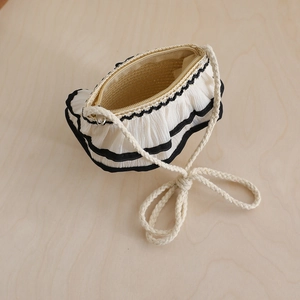 Detail of a mini pleated shoulder bag with wavy texture and rope strap on wood background