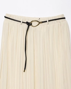 Détail d'une jupe mi-longue plissée crème avec fine ceinture noire et boucle dorée