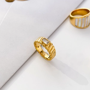 Makroaufnahme des goldfarbenen Rings mit rechteckigem Kristall und Wellenstruktur