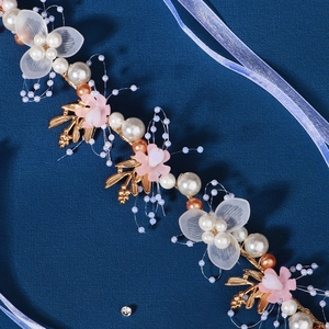 Detail of bridal hairband with handmade golden leaves, pearls and delicate fabric flowers