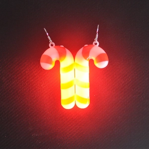 Detail view of LED candy cane earrings glowing with red, yellow, and green stripes
