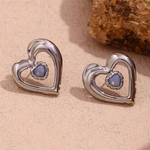 Detail showing silver hollow heart earrings with blue opal-like stone inlay in studio light