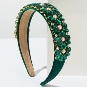 Detailed macro of baroque headband with green crystals and pearls on green velvet fabric