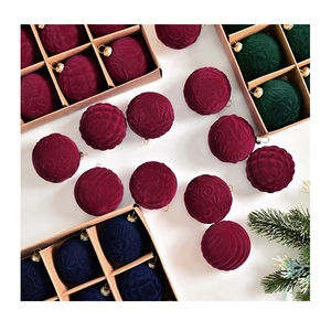 Detailed view of velvet embossed Christmas balls in dark red and blue with gold hangers