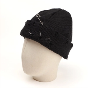 Detail of black knit beanie with silver rings and decorative safety pin in punk style