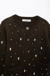 Close-up of brown knit cardigan neck label with size information and crystal detailing