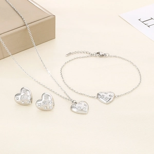 Detailed view of silver heart jewelry set with necklace, bracelet, and zircon earrings