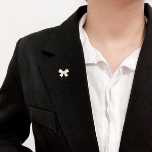 Detail of a gold bow brooch with crystals pinned on a black suit lapel for women