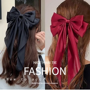 Detail of large satin bow hair clip in black and burgundy with long streaming ribbons
