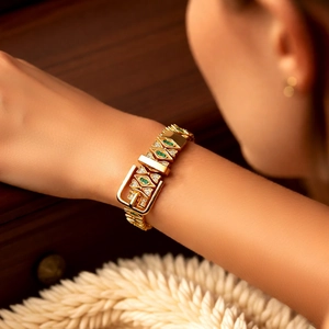 Detail of 18k gold-plated buckle bracelet featuring green and white gemstone accents