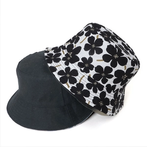 Detail view of double-sided cotton bucket hats with solid black and floral print patterns