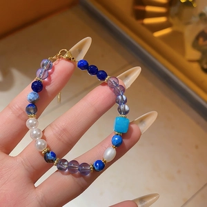 Detailed close-up of a blue zircon crystal beaded bracelet with white pearl accents