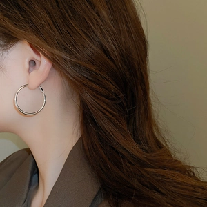 Silver hoop earrings shown on a model's ear for a stylish minimalist jewelry look