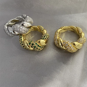 Three twisted gold and silver rings with cubic zirconia crystals on gray silk fabric