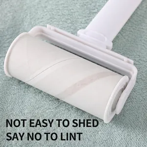 Portable lint roller with white ergonomic handle on a soft green carpet surface