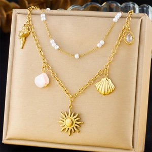 Detail of layered gold necklace with mini pearls, shell and sun pendants on display