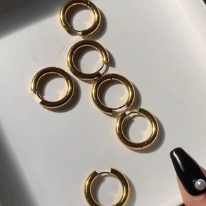 Close-up of classic golden stainless steel hoop earrings on a clean white tray