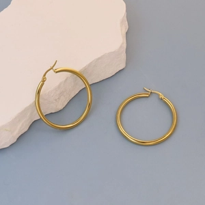 Close-up of golden flat hoop earrings with polished finish and latch back closure
