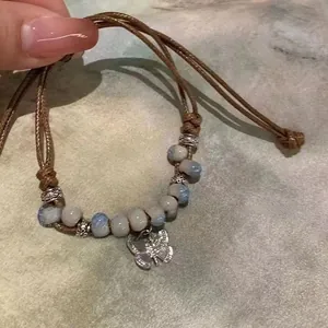 Detail of handmade bracelet with ceramic beads and silver hollow butterfly charm on green cloth